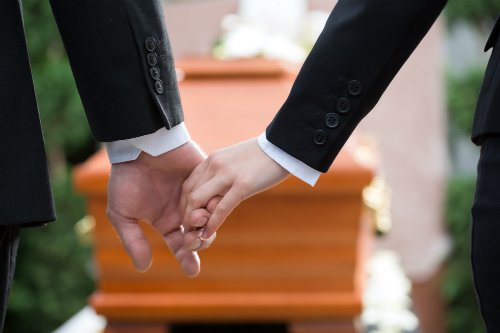 Holding hands in front of casket